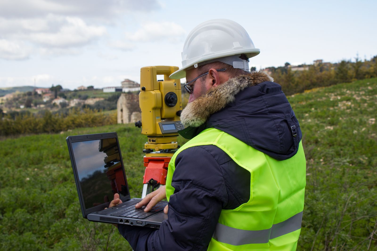 A professional surveyor, equipped with a laptop, utilizes Theodolite to conduct modern surveying