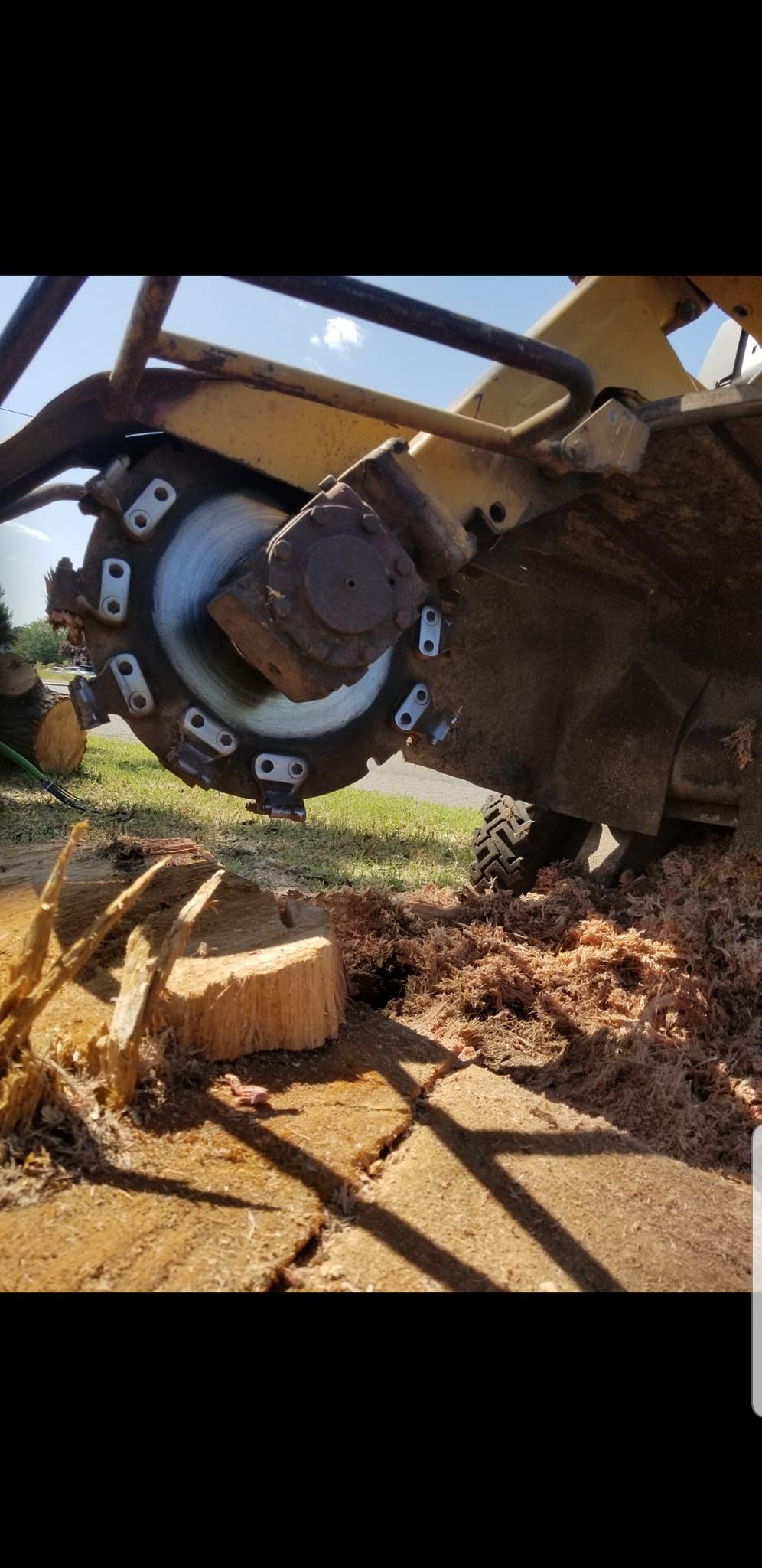 A close up of a machine cutting a tree stump.