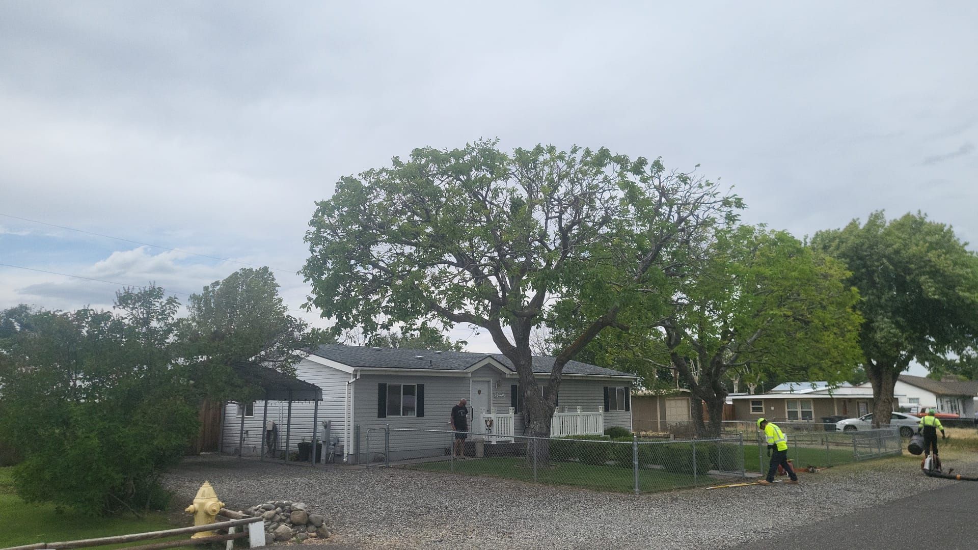 A man in a yellow vest is walking in front of a house.