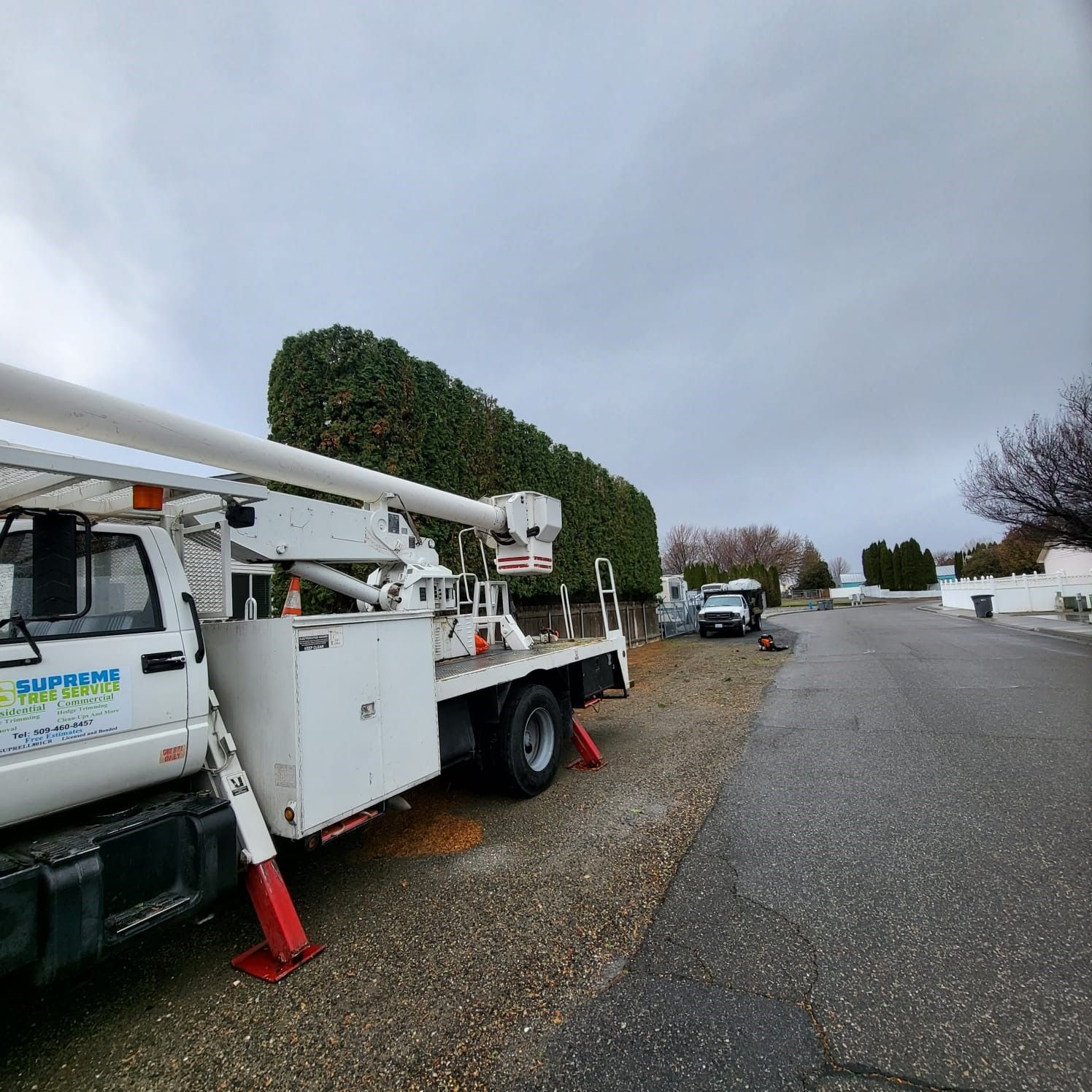 A white truck with a crane on top of it is parked in a parking lot.