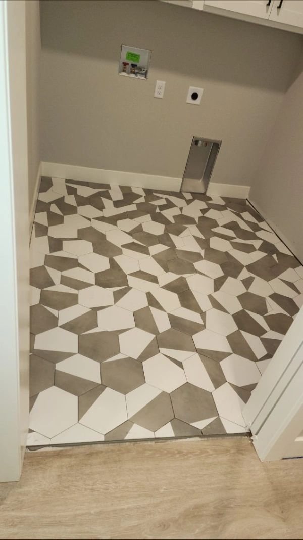 Bathroom under renovation with patterned tile floor and wall plumbing fixtures above a beige threshold