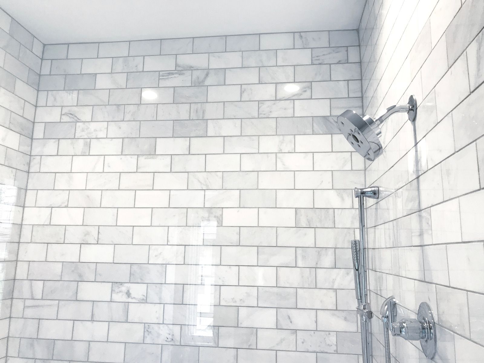 Small bathroom with a white shower-tub combo, beige tile floor, and overhead light.