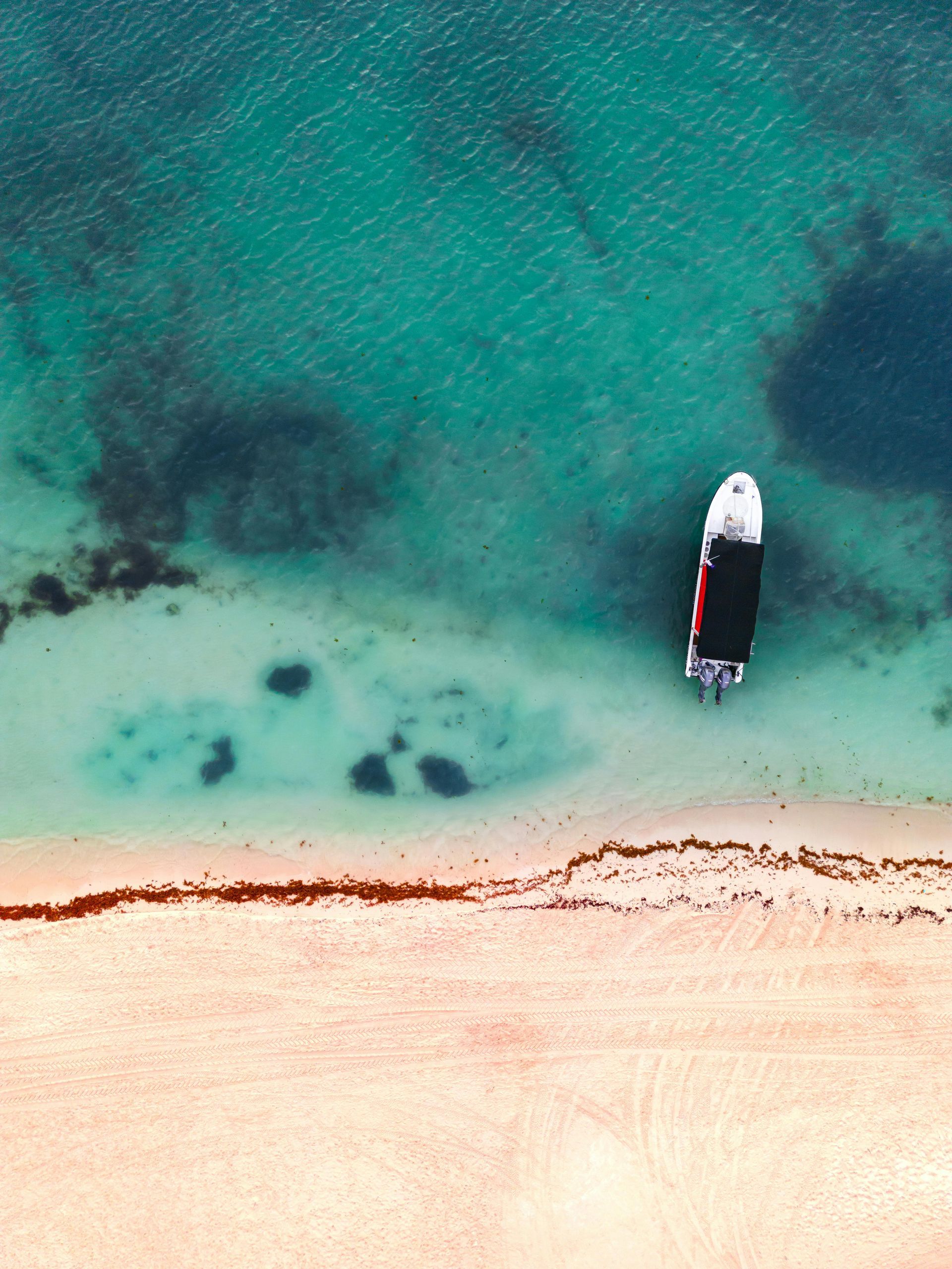 Holidays to Mexico - An aerial view of a boat in the ocean near a beach. Playa del Carmen