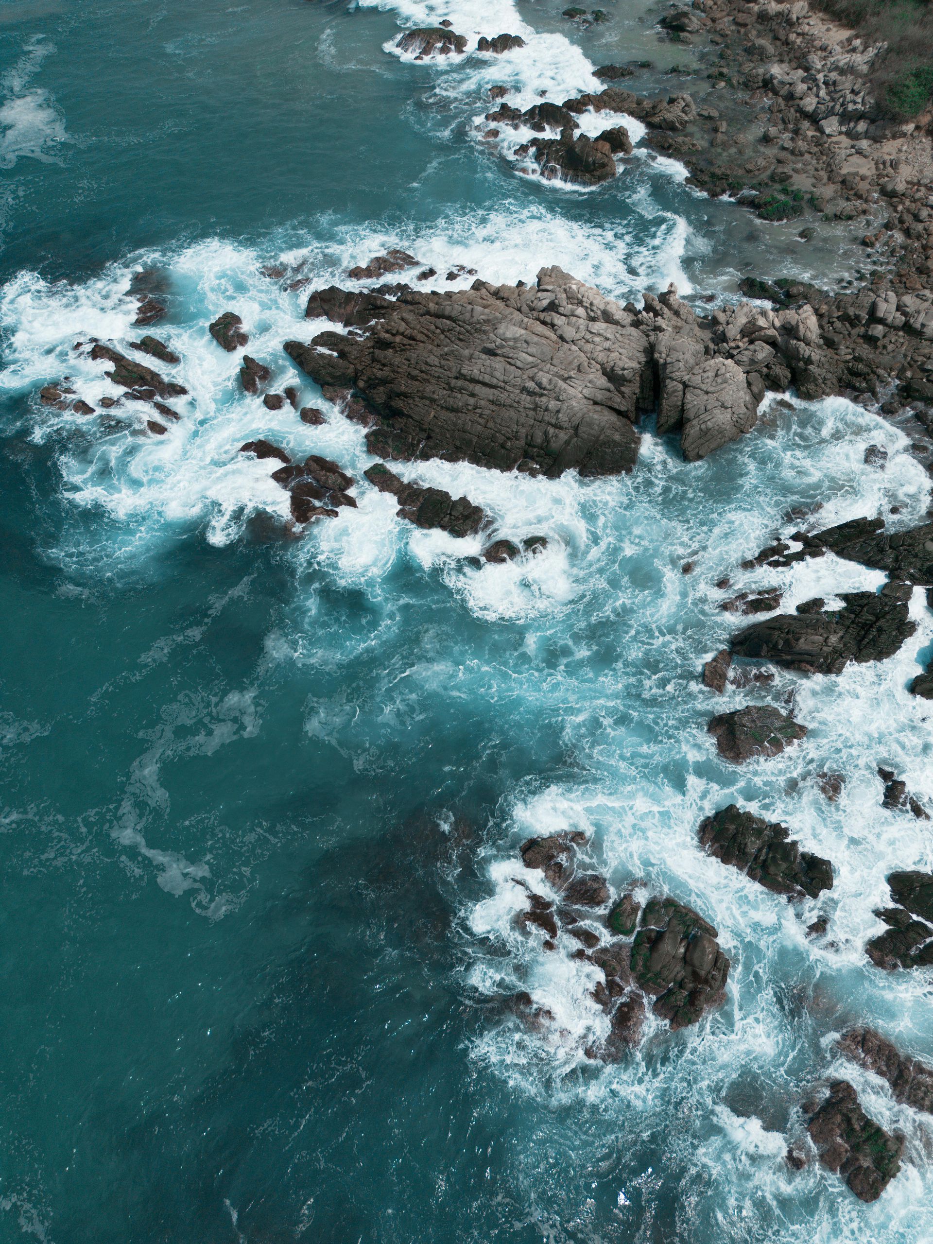 Holidays to Mexico - An aerial view of waves crashing against a rocky shoreline. Puerto Escondido