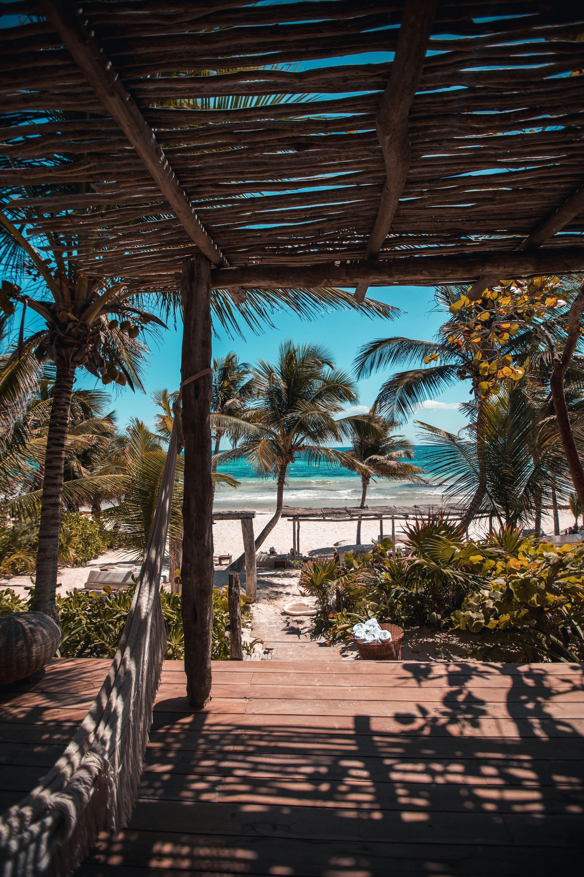 Holidays to Mexico - A wooden pergola overlooking a beach with palm trees and a view of the ocean. Tulum
