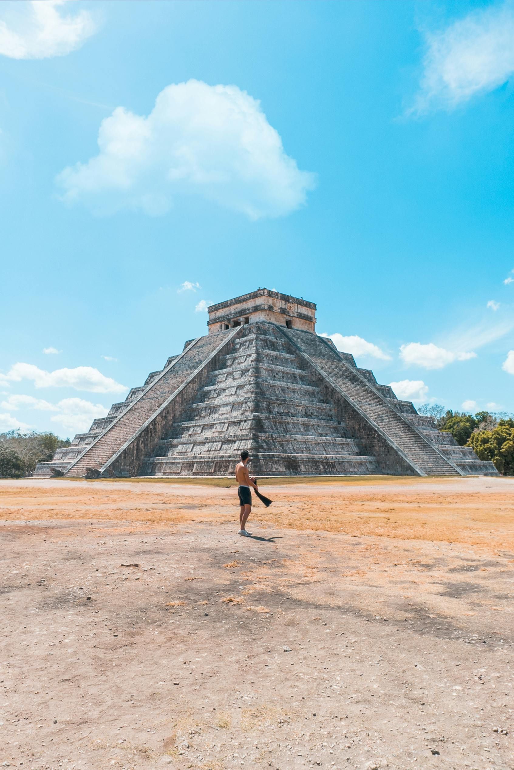Holidays to Mexico - A man is standing in front of a large pyramid. Valladolid and Chechen Itza