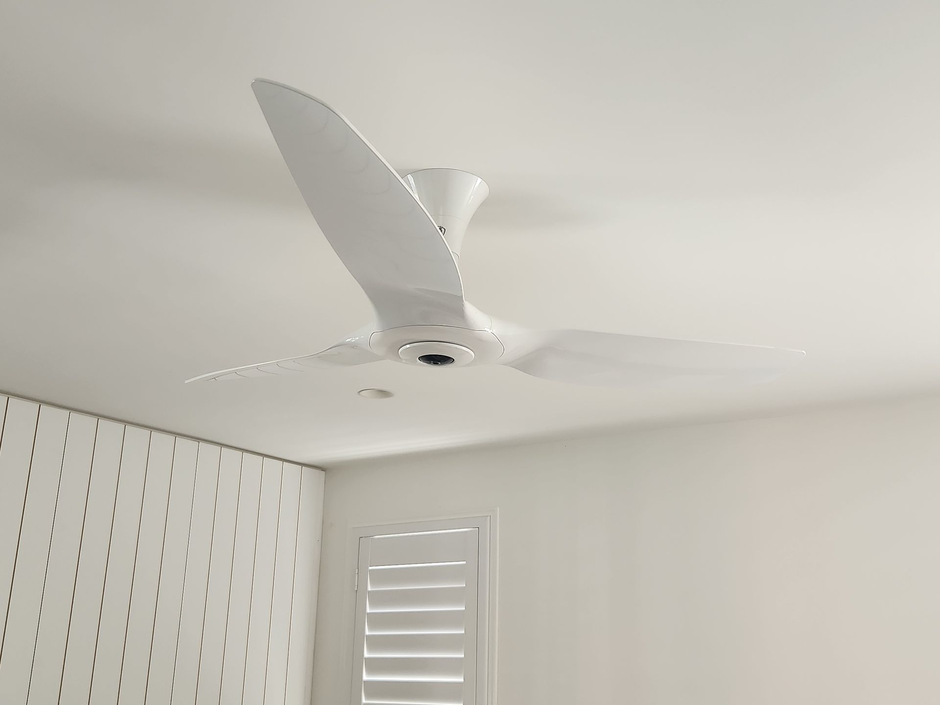 A Man is Installing a Ceiling Fan in a Living Room — Riselectrical In Yatala, QLD