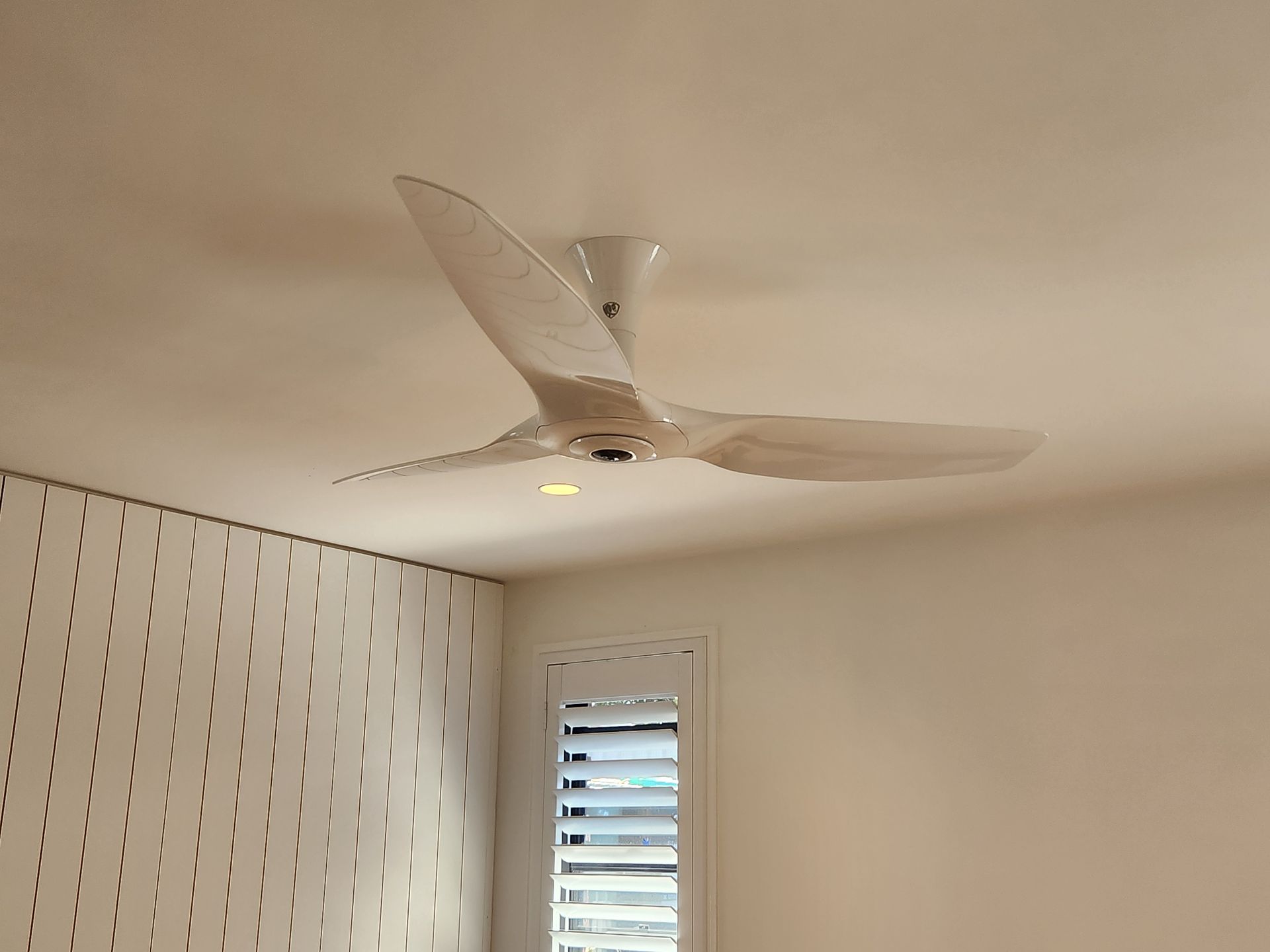 A Man is Installing a Ceiling Fan in a Living Room — Riselectrical In Currumbin, QLD