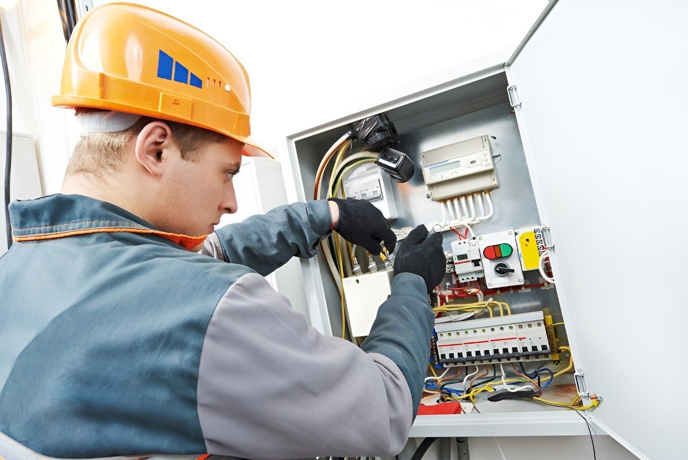 A Man Wearing a Hard Hat is Working on an Electrical Box — Riselectrical In Currumbin Waters, QLD