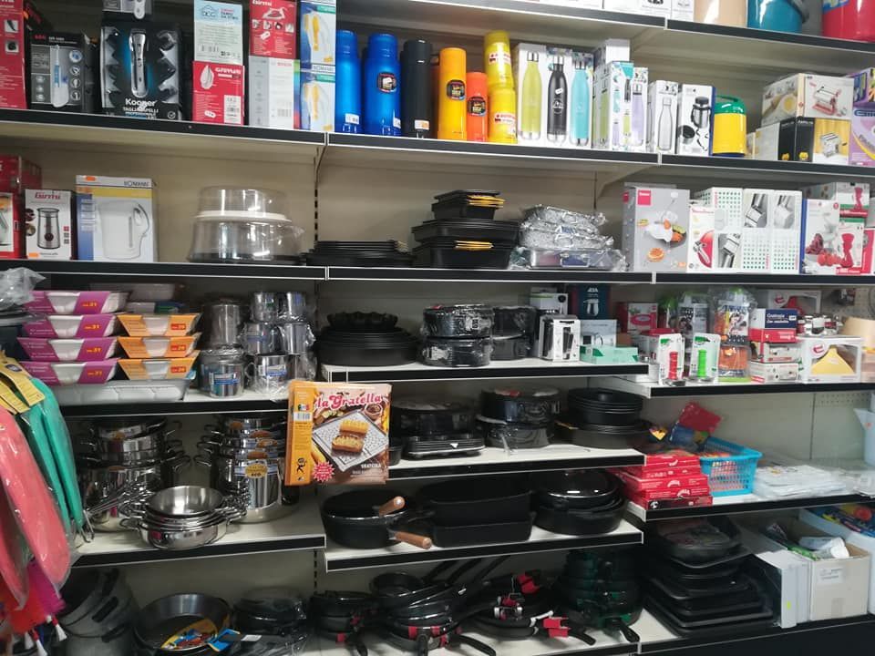 Uno scaffale di un negozio pieno di vari articoli, tra cui pentole e padelle.