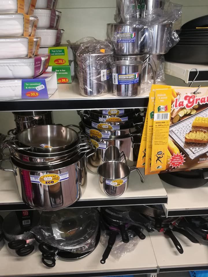 Uno scaffale di un negozio pieno di pentole e padelle in acciaio inossidabile.