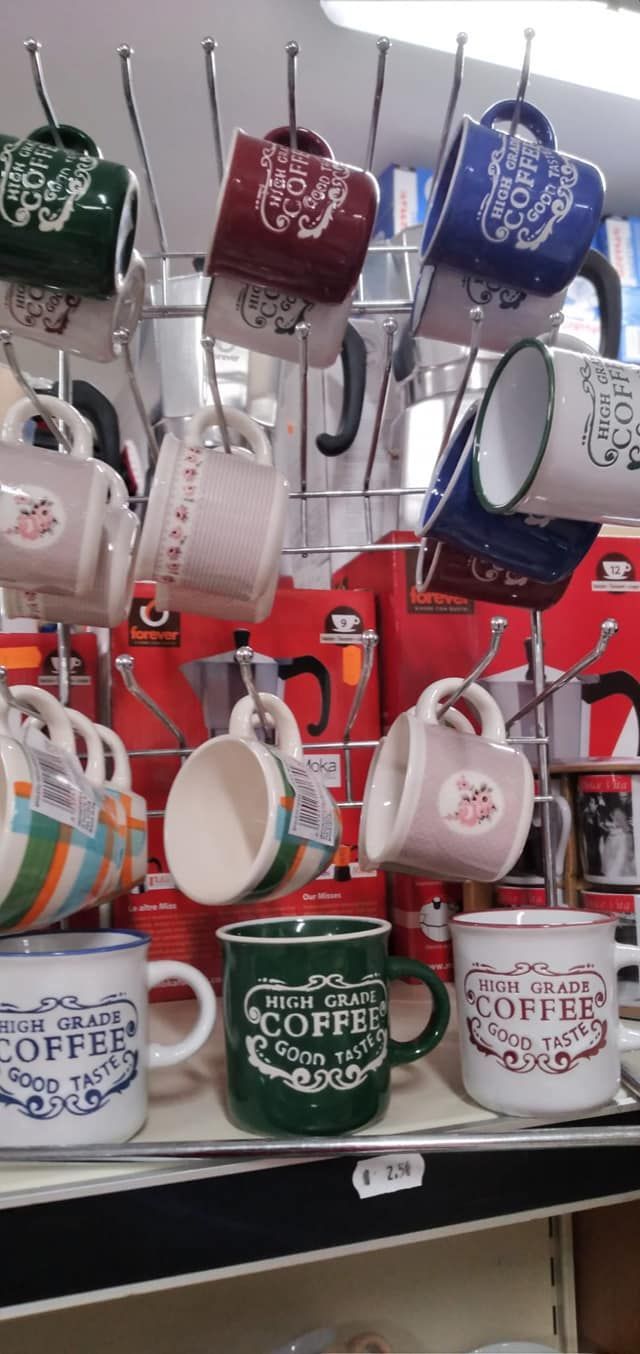 Un mucchio di tazze da caffè appese a uno scaffale in un negozio