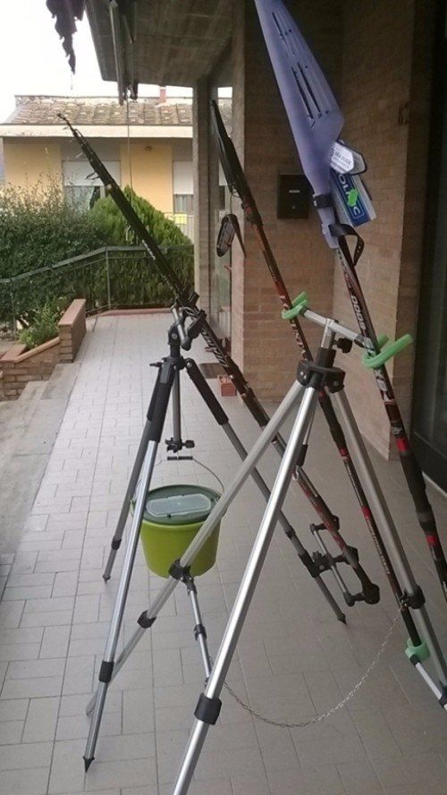 Un mucchio di canne da pesca sono appoggiate su un treppiede su una veranda.