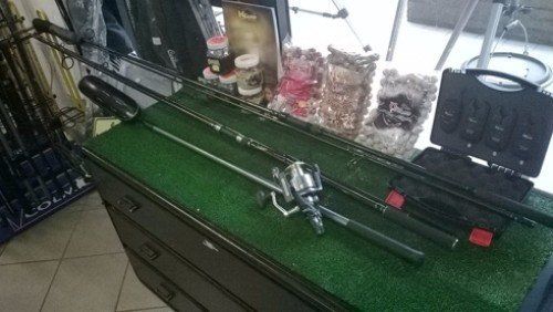 Una canna da pesca e un mulinello sono appoggiati su un tavolo verde.