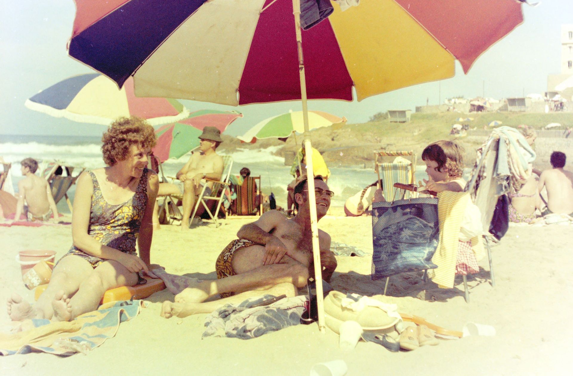 A young Lisa telling her parents a story on the beach during a family holiday