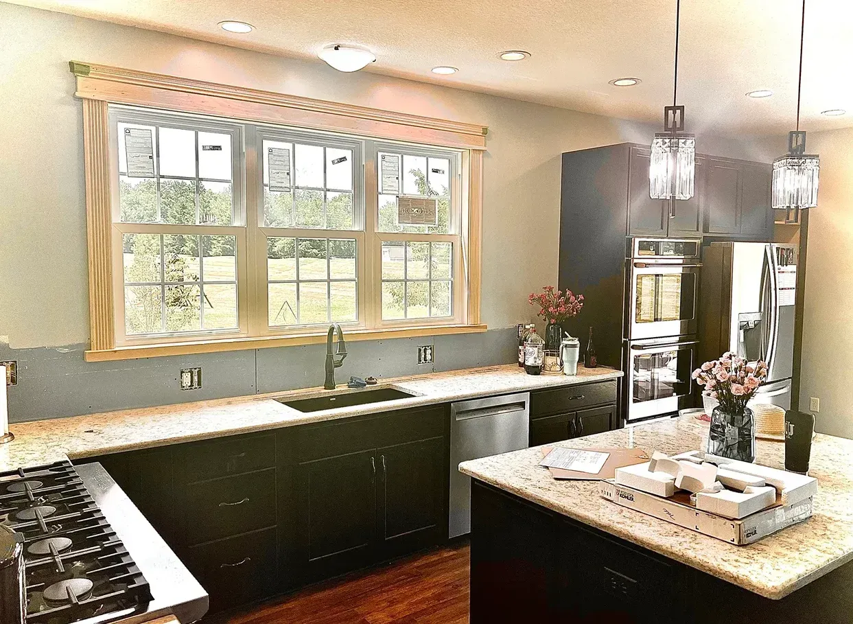 Kitchen interior with dark cabinets, granite countertops, and a window overlooking a green field.