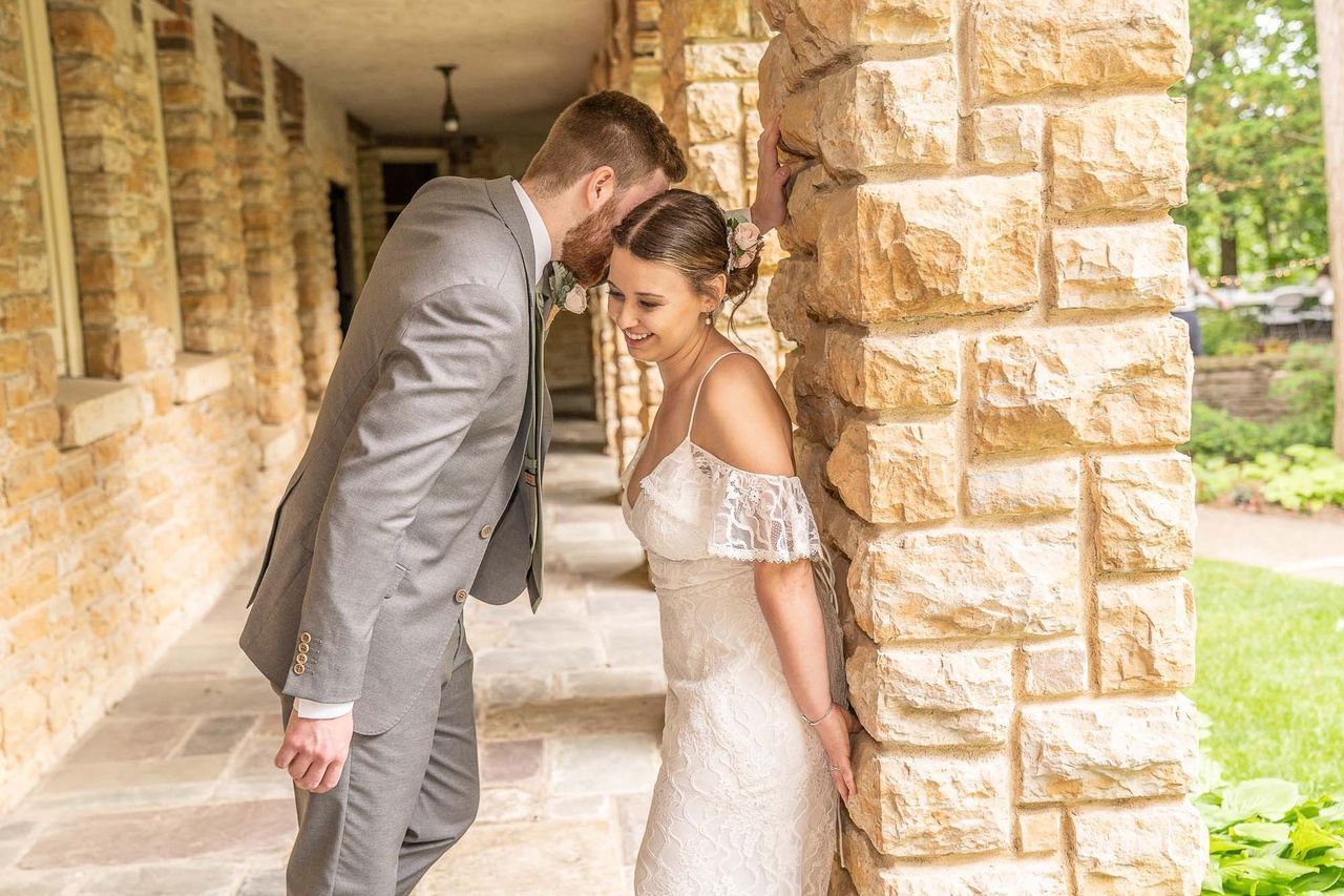A bride and groom are leaning against a brick wall.