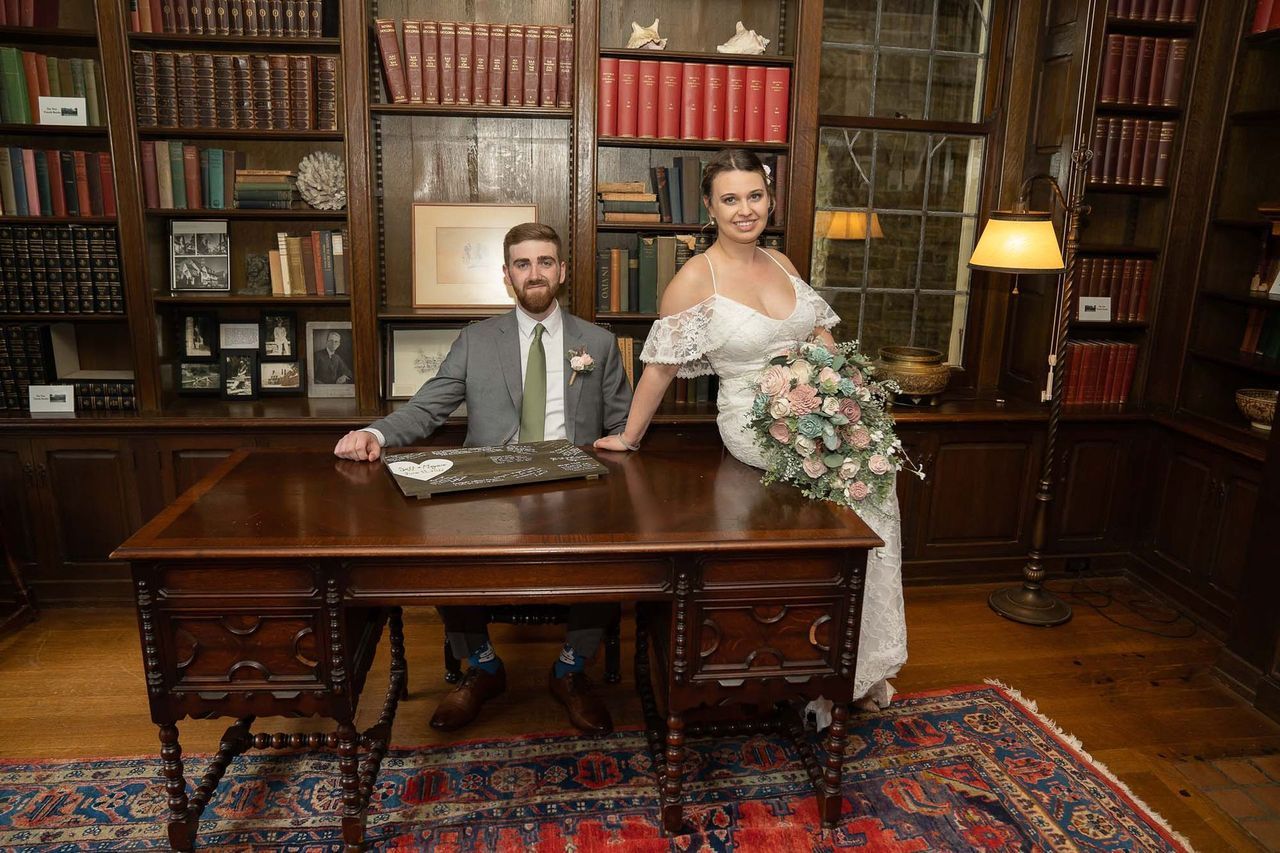 A bride and groom are posing for a picture in a library.