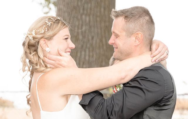 A bride and groom are hugging and looking at each other.