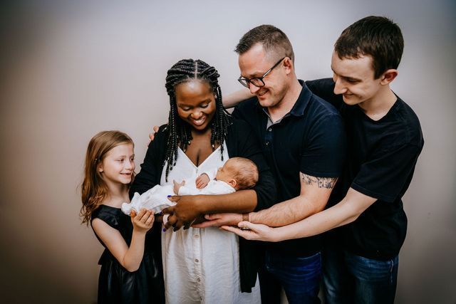 A family is posing for a picture with a newborn baby.