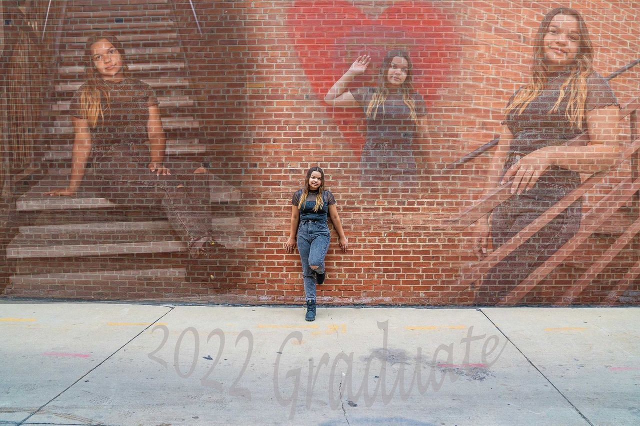 A woman is standing in front of a brick wall.