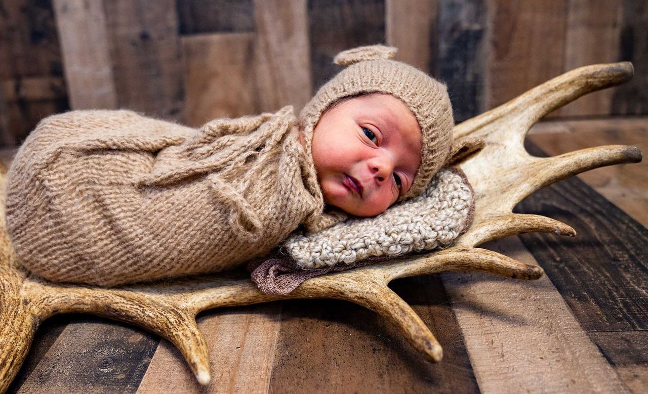 A baby wrapped in a blanket is laying on antlers.