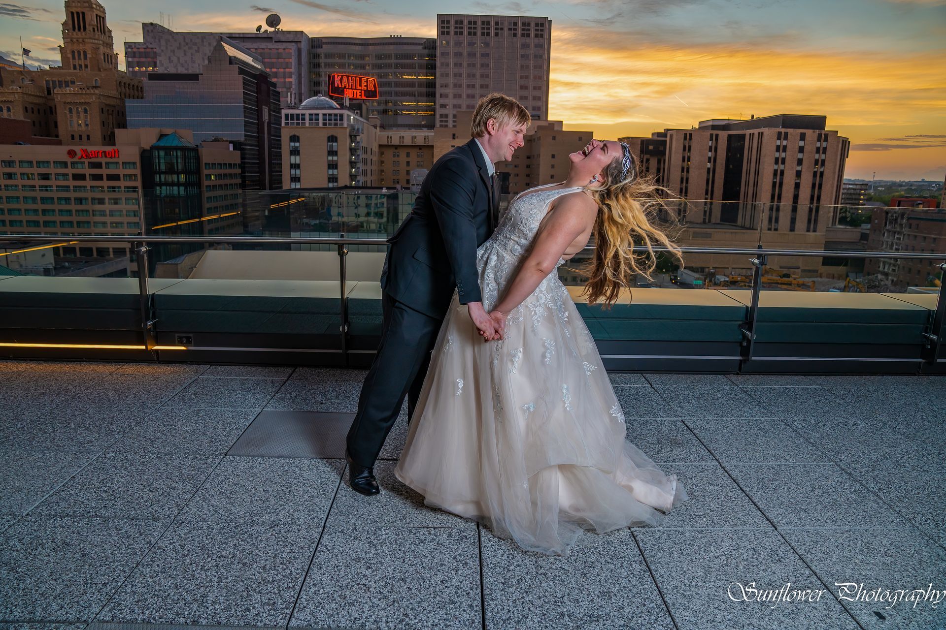 A bride and groom are posing for a picture on a rooftop.