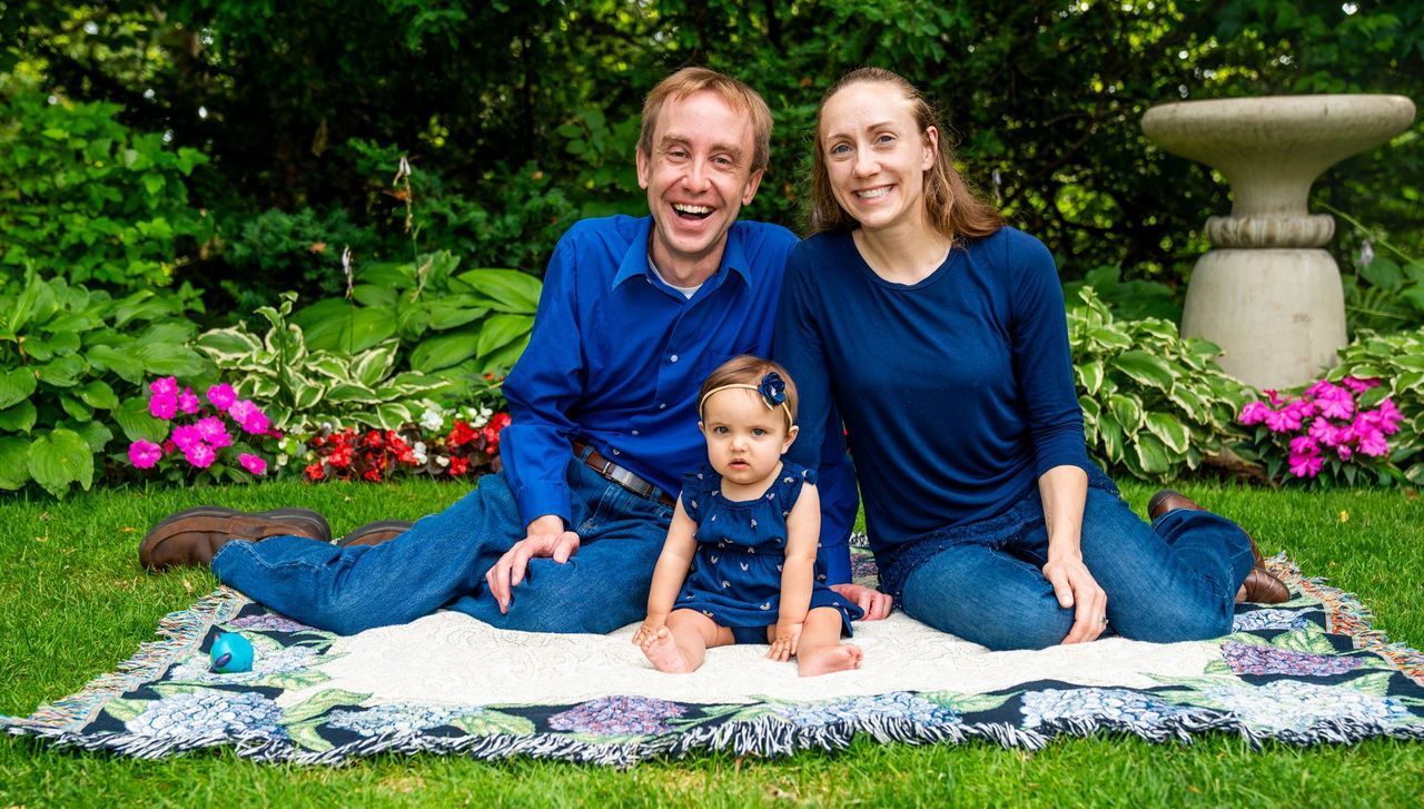 A family is posing for a picture while sitting on a blanket in the grass.