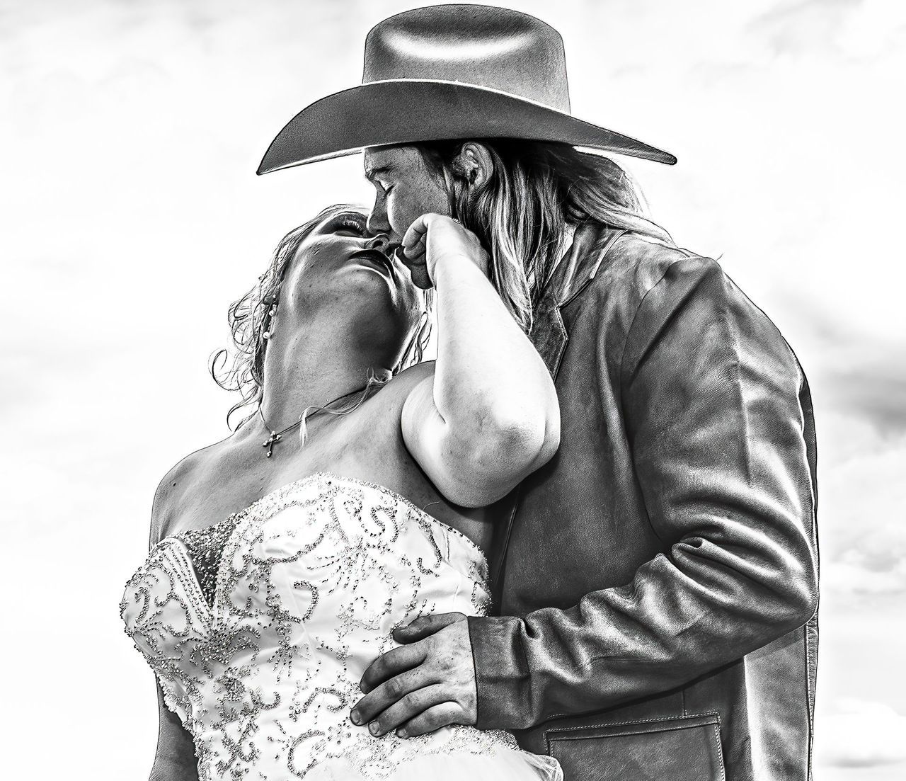 A man in a cowboy hat is hugging a woman in a wedding dress