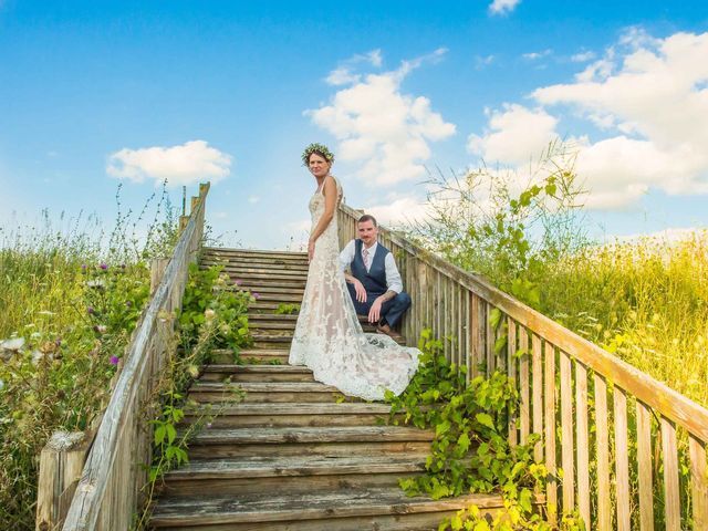 A bride and groom are posing for a picture on a wooden bridge.