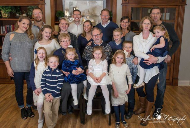 A large family is posing for a picture together in a living room.