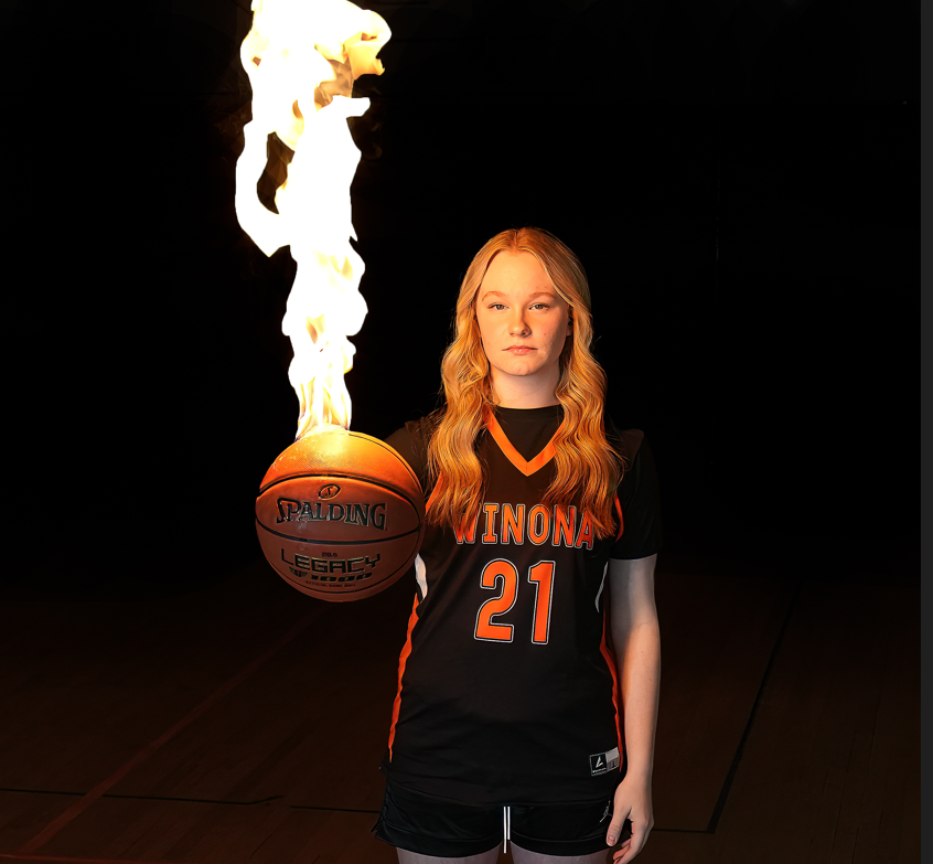 A woman holding a spalding basketball with flames coming out of it