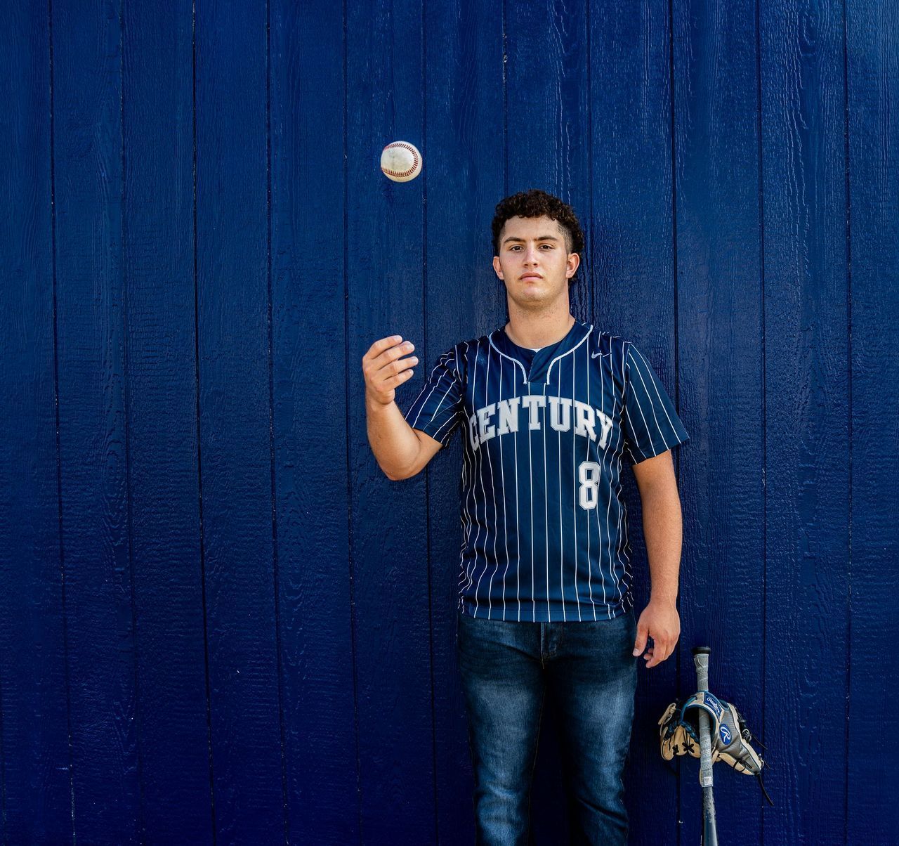 A young man in a century 8 jersey is throwing a baseball