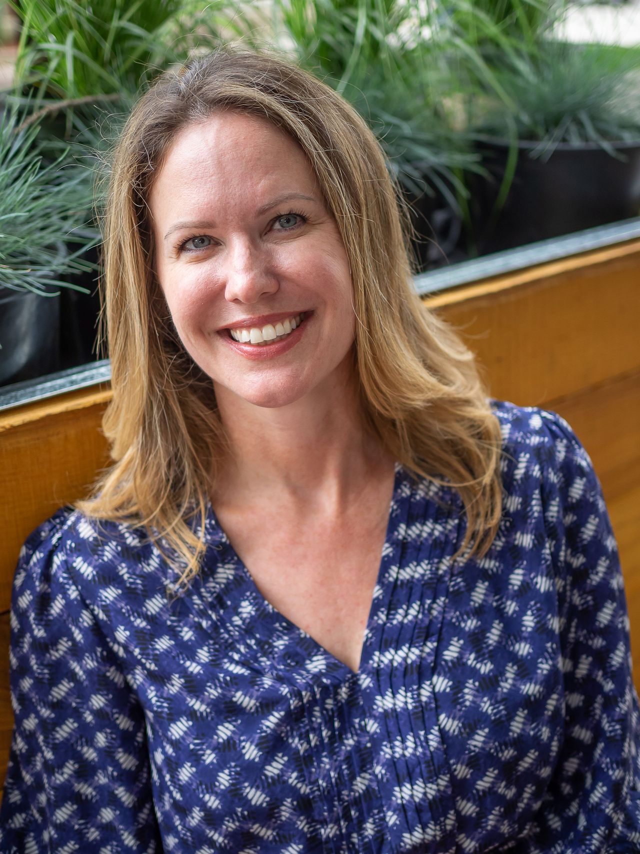A woman in a blue shirt is smiling for the camera.