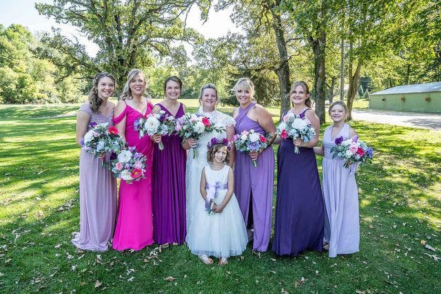 A bride and her bridesmaids are posing for a picture in a field.