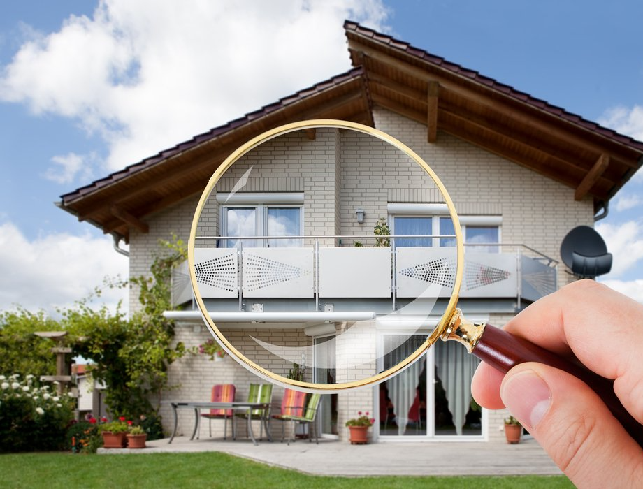 A person is holding a magnifying glass in front of a house