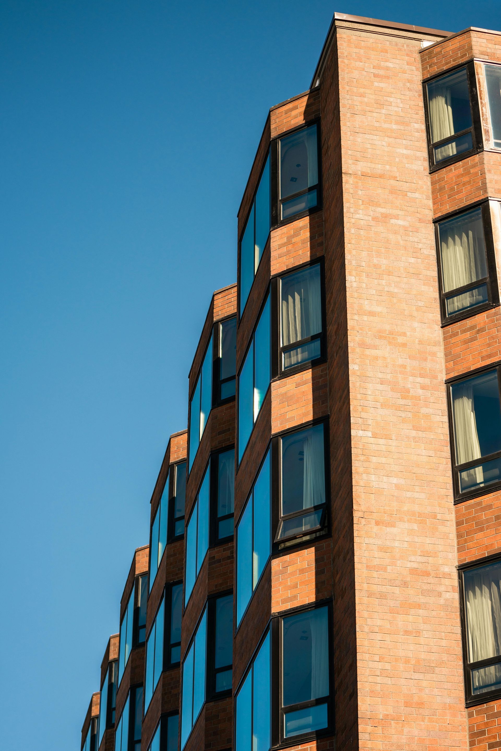 Un grand bâtiment en briques avec beaucoup de fenêtres contre un ciel bleu.