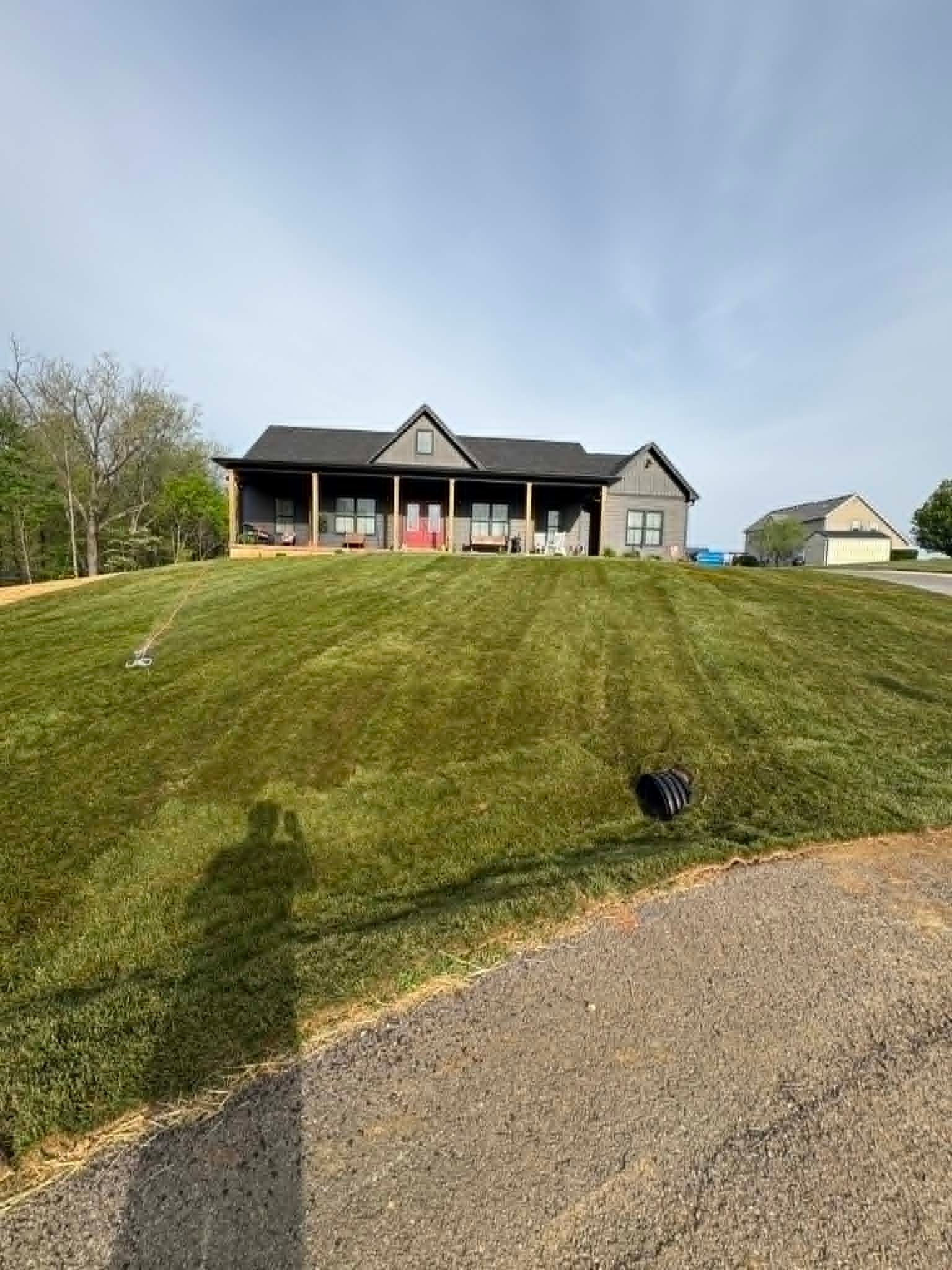 Red wooden playset with a green roof in a grassy backyard.