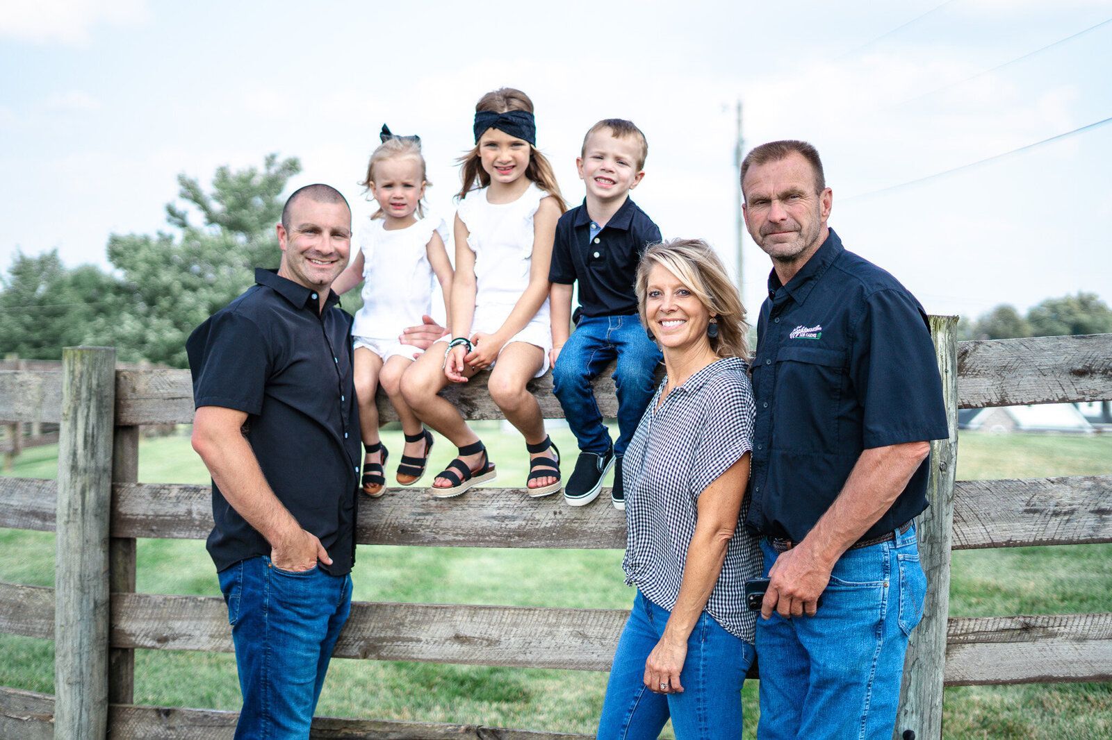 A family is posing for a picture in front of a wooden fence.