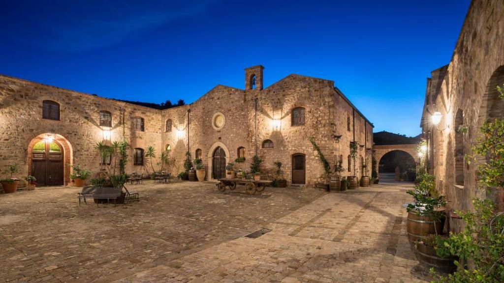 Piscina con vista sul mare, con una chiesa e un'isola sullo sfondo, sotto un cielo azzurro brillante.