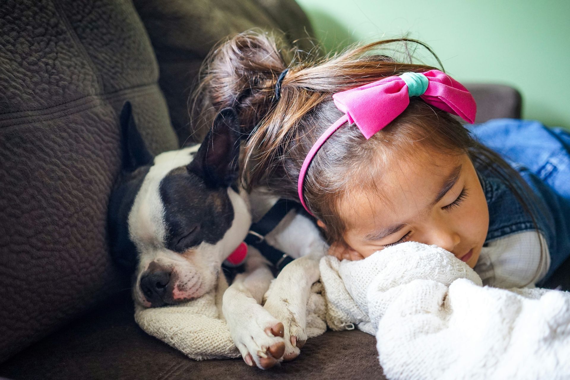 A little girl is laying on a couch with a puppy.