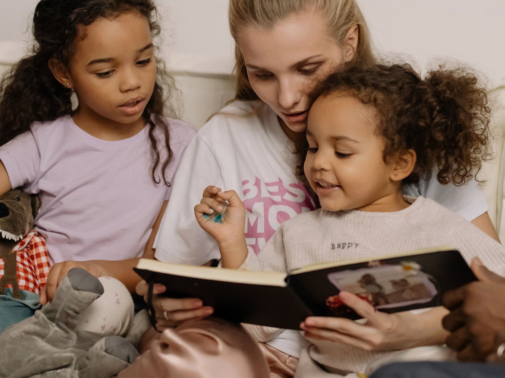 a woman is reading a book to two little girls .