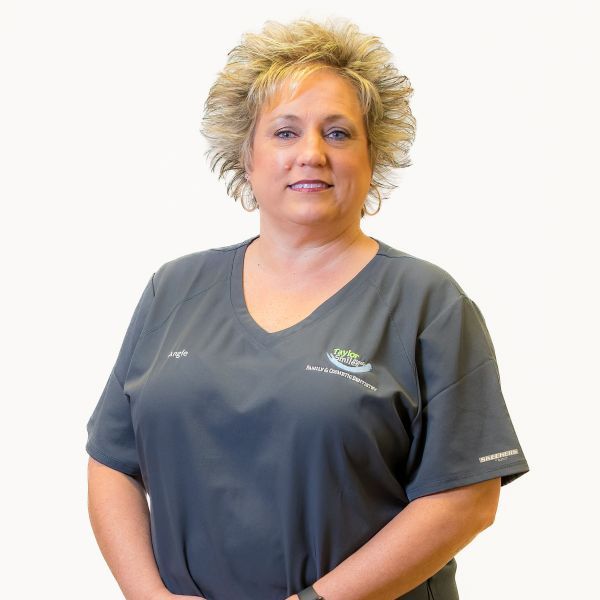 a woman wearing a gray scrub top is standing in front of a white background
