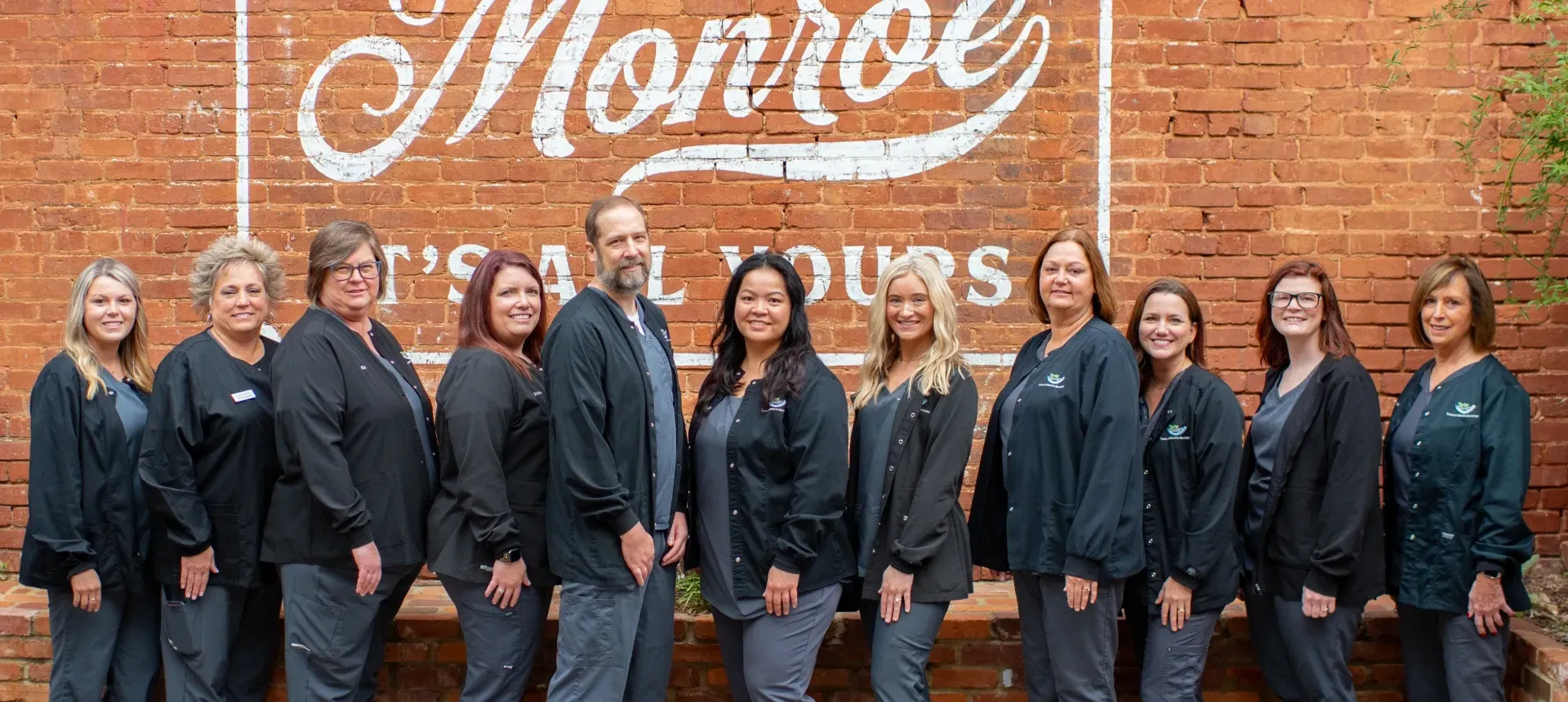 A group of people are posing for a picture in a dental office.