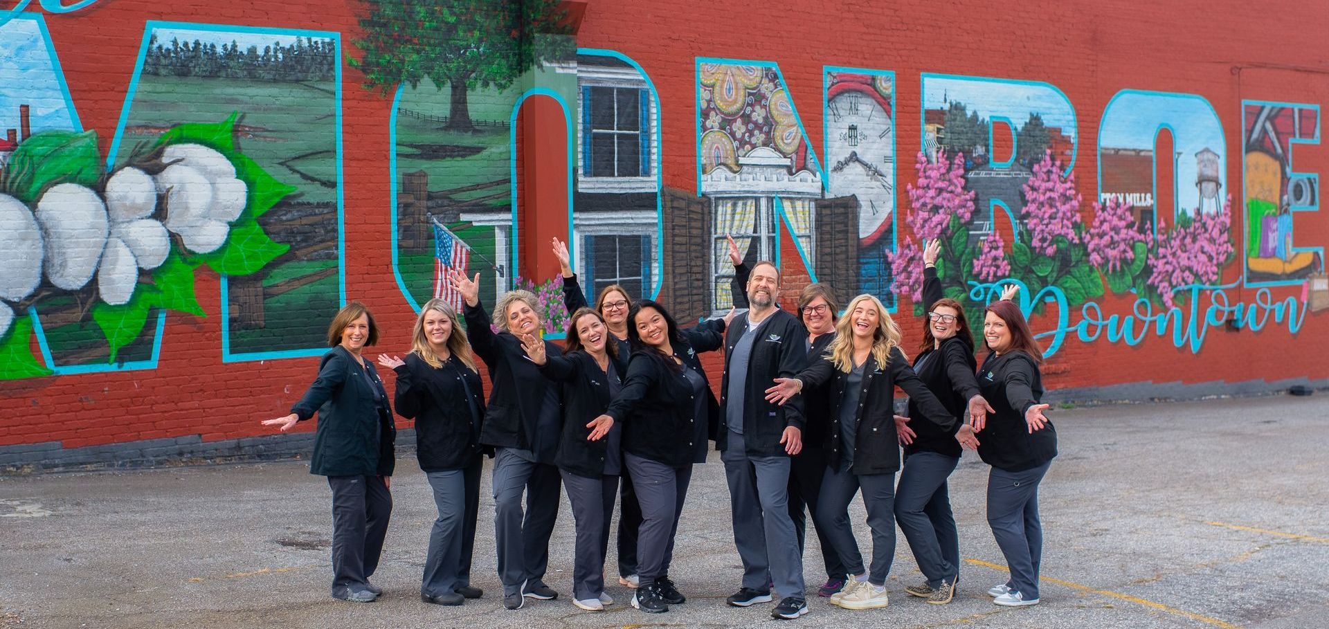 A group of people are posing for a picture in front of a mural.