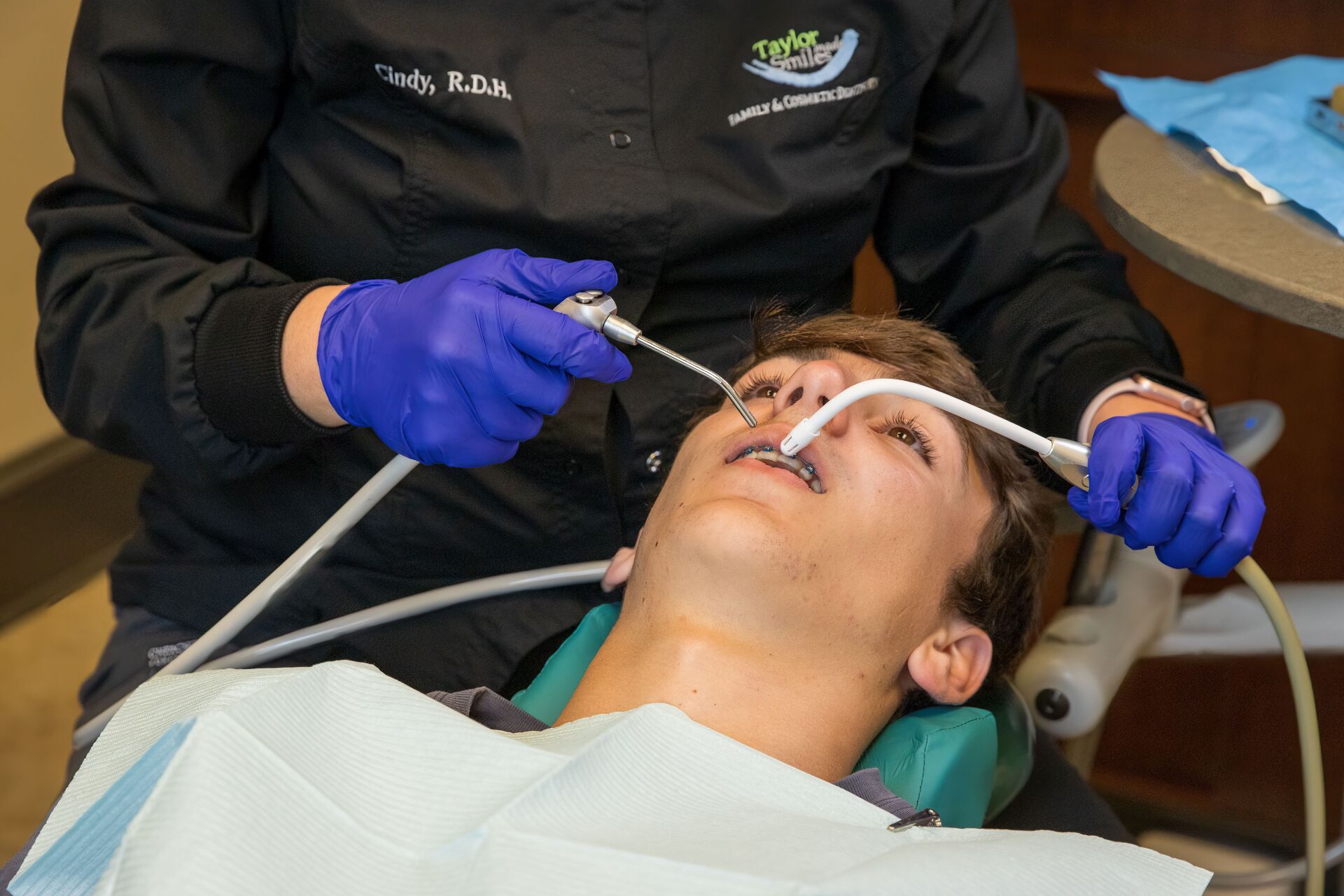 A dentist is examining a young boy 's teeth in a dental chair.
