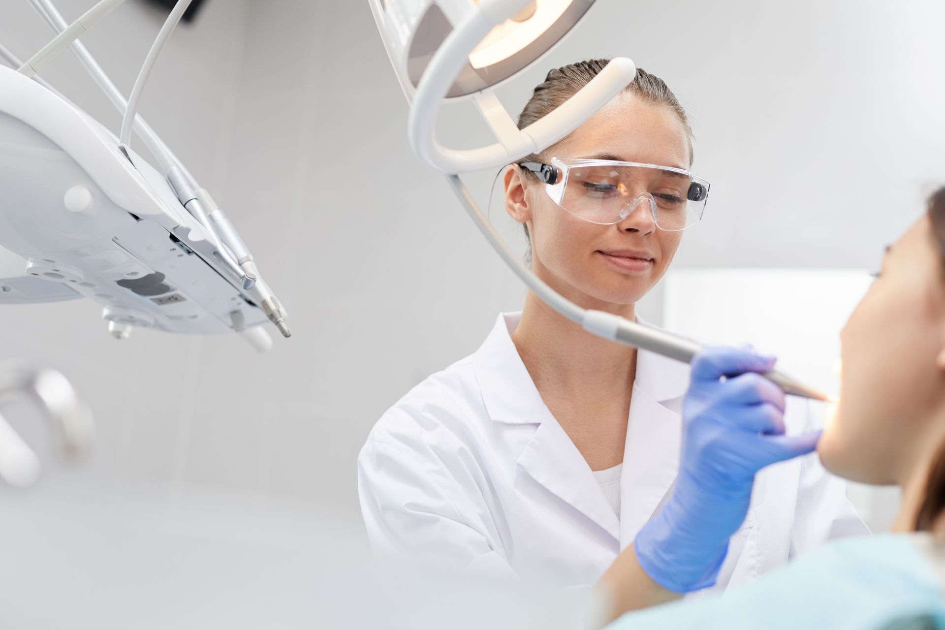 A female dentist is examining a patient 's teeth in a dental office.