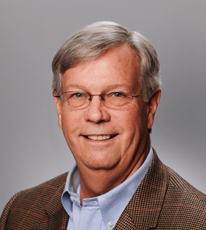 a man wearing glasses and a suit is smiling for the camera .