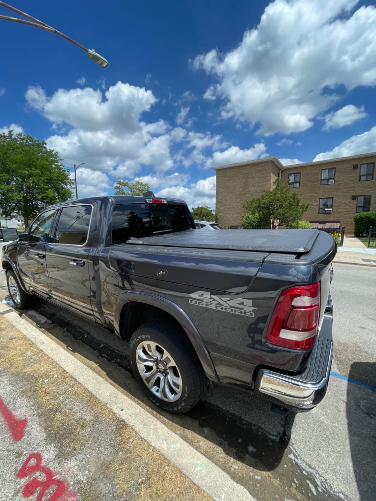 A black ram truck is parked on the side of the road in a parking lot.