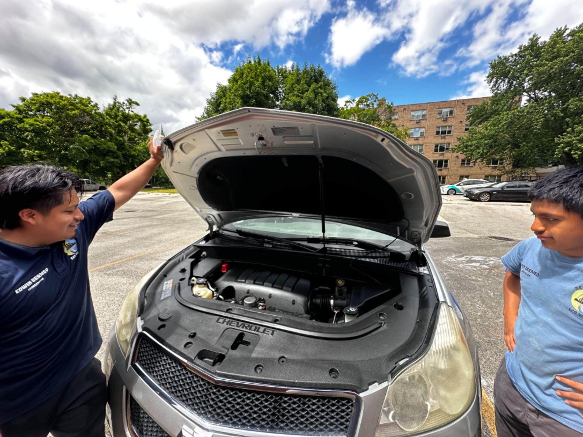 Two men are looking under the hood of a car.